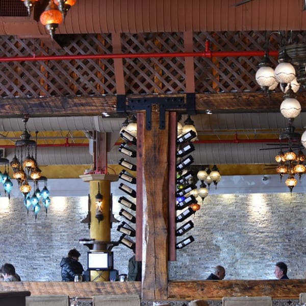 Opera Cafe Lounge interior with Turkish lamps, a wine rack column, and patrons dining.