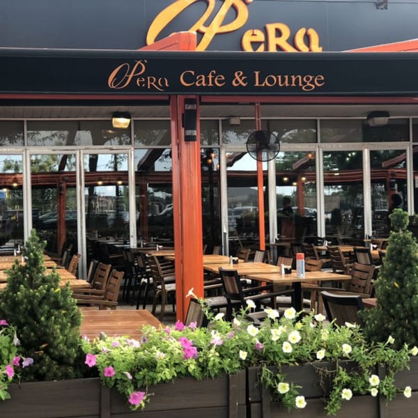 Opera Cafe Lounge exterior with outdoor seating, wooden tables, chairs, and flower boxes.