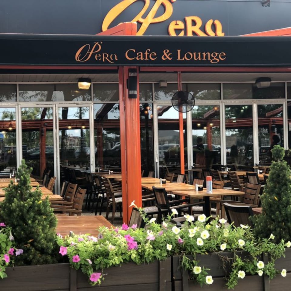 Opera Cafe Lounge exterior with outdoor seating, wooden tables, chairs, and flower boxes.