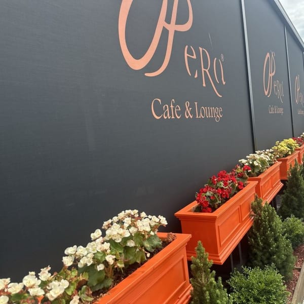 Opera Cafe Lounge's black exterior wall with orange lettering and vibrant flower boxes.