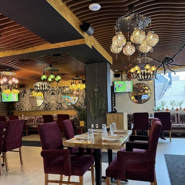 Opera Cafe Lounge interior with ornate Turkish lamps, patterned walls, and burgundy chairs around wooden tables.