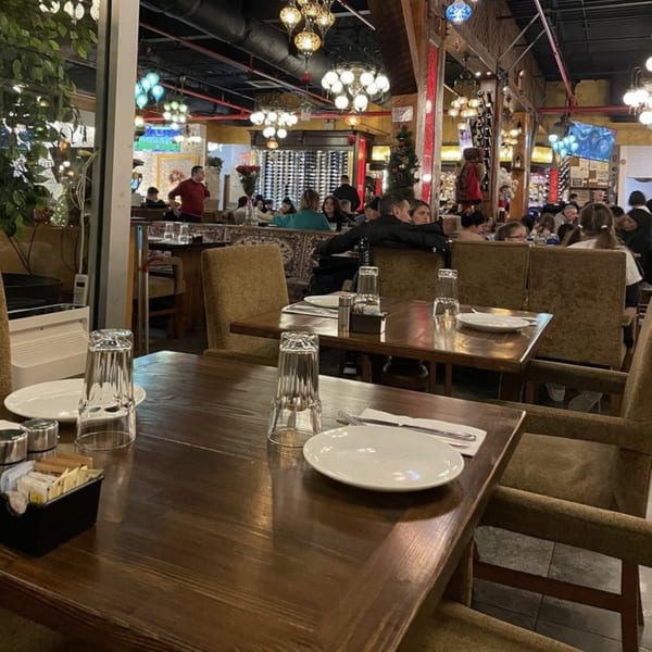 A bustling Turkish restaurant interior with ornate lighting, set tables, and patrons dining.
