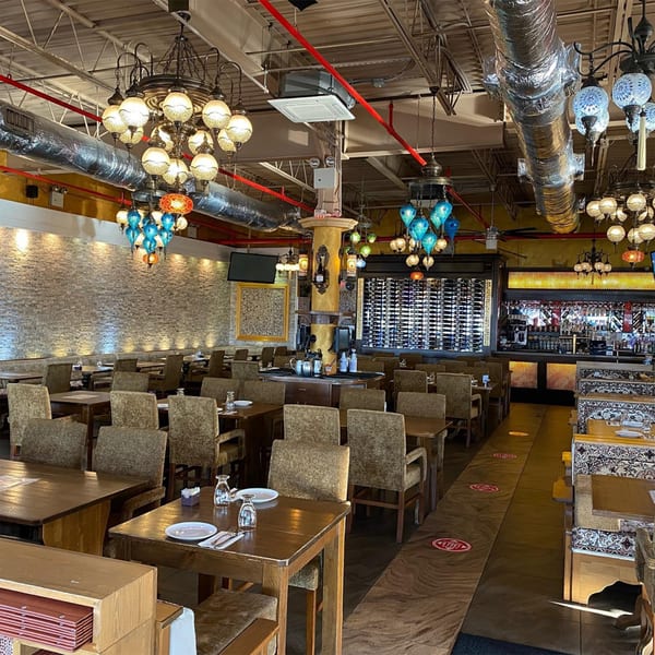 Opera Cafe Lounge's dining room with Turkish chandeliers, wooden tables, and a bar area.